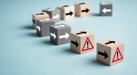 Wooden blocks with arrows and warning signs illustrate risk management and strategic direction on a blue background representing business challenges and potential dangers ahead in planning