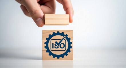 Hand placing a wooden block on top of iso certified blocks showcasing quality management and standards compliance for business excellence and operational efficiency in a global market