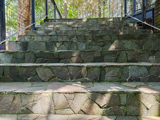 Modern park bridge and stone stairs with metal mesh railings