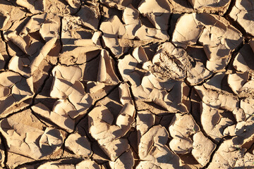 Dried desiccated mud texture in the bottom of an empty resevoir during a drought, environmental issues, climate change, global warming, natural disaster