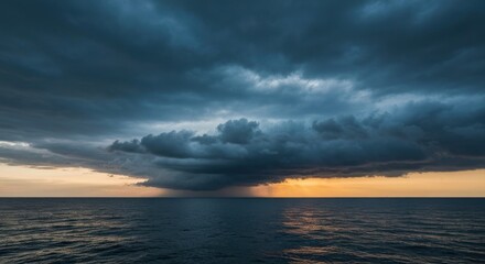 Dramatic storm clouds gathering over a still ocean at sunset