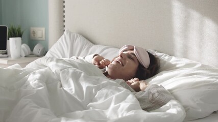 A cute, beautiful woman in pajamas waking up and stretching in bed in the morning. Concept morning freshness.
