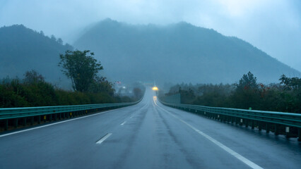 Misty road with mountains in the distance on a rainy day