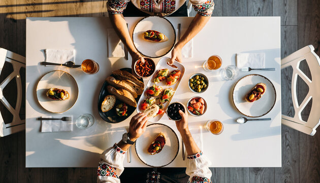 Overhead view of a delicious brunch table setting, featuring various food and drinks with people enjoying their meal. - Powered by Adobe