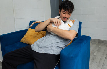Man sitting on the sofa in his living room, petting and holding his cat, showing tenderness and connection with his pet at home