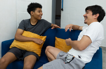 Two friends sitting on the living room sofa chatting happily, enjoying a friendly and relaxed moment at home