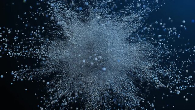 Particles forming intricate structures before dispersing outward in dynamic motion on dark background.