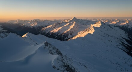 Snowy mountain peaks at dawn. Vast, sunlit alpine landscape