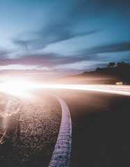 Dramatic Sunset Over a Sparkling Beach with Distant Silhouetted Hills and Dramatic Clouds Illuminated by Bright Sun Flare