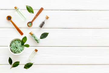 Obraz na płótnie Canvas Organic cosmetics products - tea tree essential oil and sea salt near green leaves top view