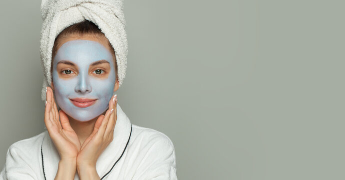 Attractive healthy woman in blue clay cosmetic face mask indoor portrait. Facial treatment and skin care concept