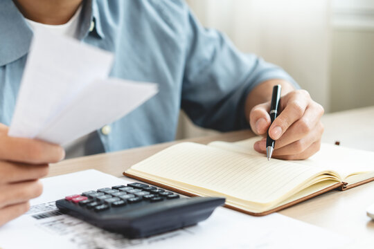 Deduction planning, debt asian accountant hand using calculator to calculating money balance from bill and income, cost budget expenses for pay money form personal individual on table at home.