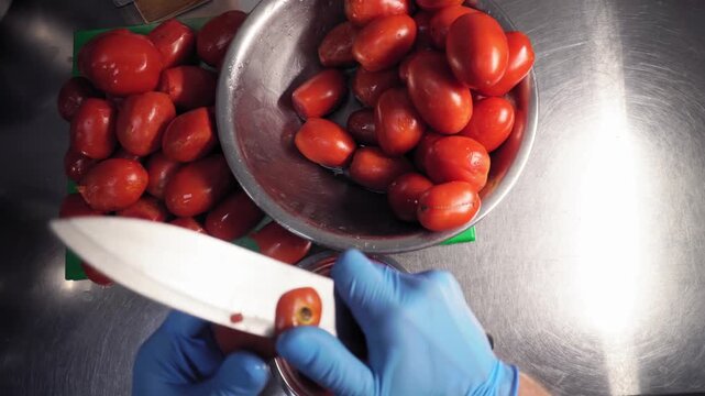 The human hands, takes tomatoes from a bowl, cuts off the unusable parts of them