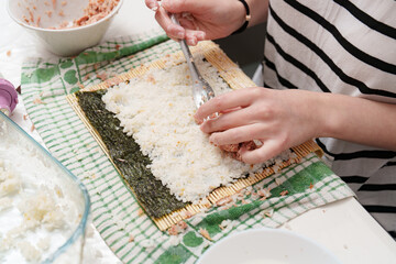 Culinary creativity unfolds making sushi at home on a summer afternoon, spreading tuna across the rice