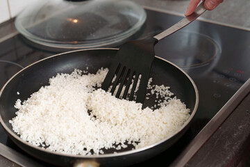Tossing freshly cooked rice with a spatula inside a pan, on a hot stove for perfect consistency and the best taste