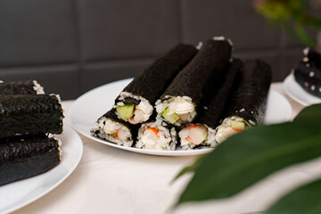Rolled and ready maki sushi on white plates shows off rice, cucumber, and crab sticks with fresh ingredients © andov