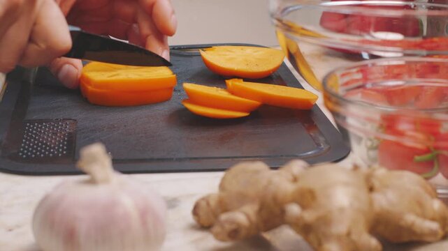 A man cuts persimmons. Persimmon salad. Healthy eating.