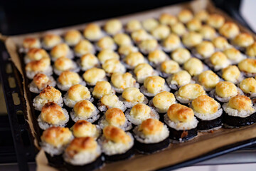 Rows of delicious baked sushi rolls with creamy toppings on a Baking Sheet