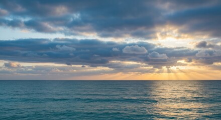 Wide shot of a tranquil sunrise over a vast ocean, with a mix of clouds