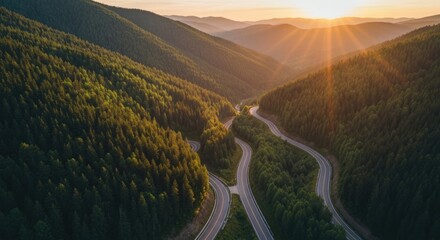 Winding mountain road through lush forest at sunset.  Aerial view