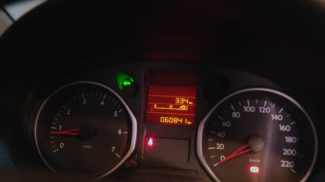 Car's instrument panel with speedometer, tachometer, and indicators lighting up during start-up