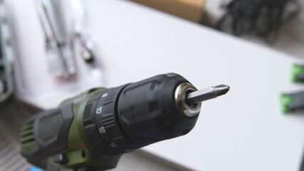 Close up of a cordless drill driver with a phillips bit spinning in a workshop