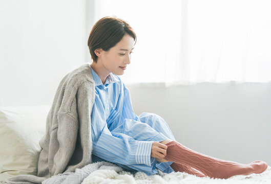 寝室で靴下を履く女性