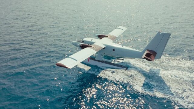 Seaplane taxiing on clear blue ocean water under bright sunny sky