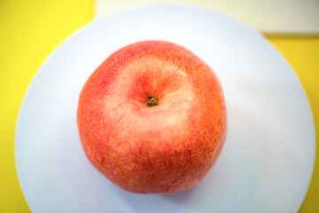 The apple on the white plate is cut in half with a knife