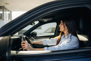 Woman is sitting in the modern car, happy new owner