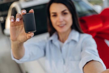 Expensive gift, present. Woman posing with a car in an auto showroom, modern dealership environment
