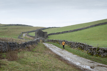 A jogger runs up a stone track on the edge of Pen-Y-Ghent in the Yorkshire Dales National Park. Shot on an overcast and wet day in the dales.