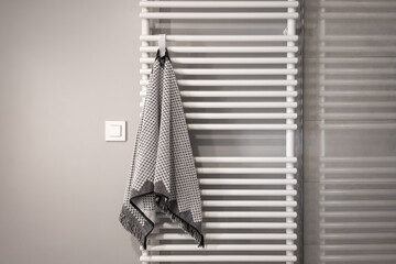 minimalist bathroom in white and grey colors with radiator and towel on it. bathroom interior with...