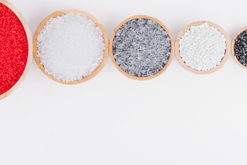 Polymer products of different colors in wooden containers on a white background. Polymers and polystyrene. Chemical industry