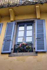 Window With Blue Shutters And Virgin Mary Statue In Lourdes France