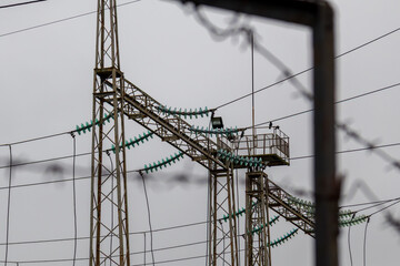 Tall transmission towers carry power lines across a desolate landscape, with a cloudy sky framing the scene in late afternoon light