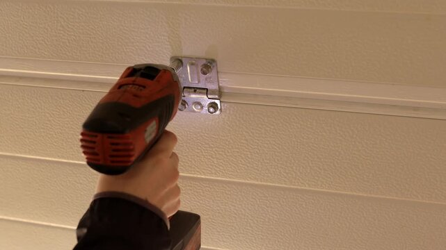 Impact driver driving screw into ceiling-side hinge bracket