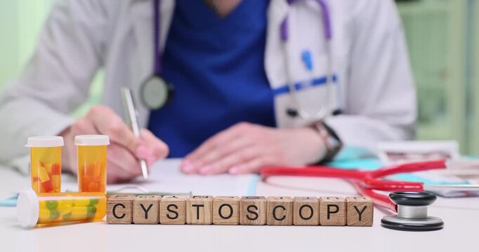 Wooden blocks spell word Cystoscopy near pill containers on table. Urology doctor writes notes scheduling cystoscopy procedure for patient case