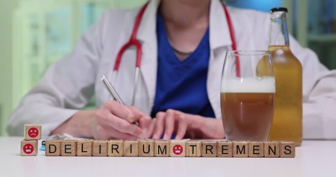Wooden cubes positioned near full beer glass and bottle spell Delirium Tremens. Doctor writes out detailed treatment plan in notebook at table