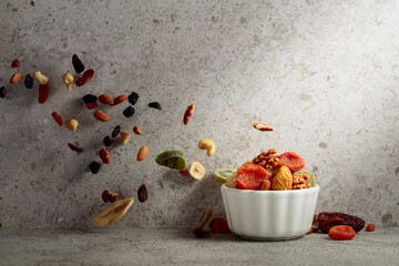 Mix of dried fruits and nuts in a white bowl.