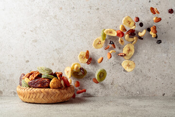 Mix of dried fruits and nuts in motion on a gray background.