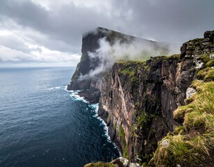 Dramatic cliffs meet the sea under a cloudy sky; lush vegetation contrasts with rocky formations