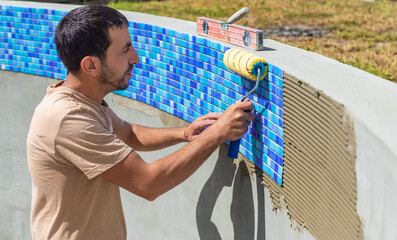 A man lays mosaic tiles in a swimming pool. Selective focus.