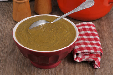Bol de soupe de petits pois avec une cuillère en gros plan servi à table avec une serviette