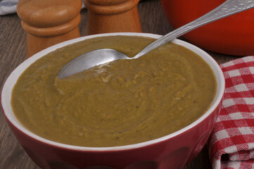 Vue partielle d'un bol de soupe de petits pois avec une cuillère en gros plan
