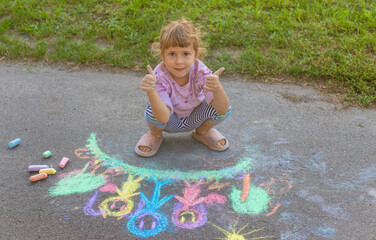 Fototapeta premium Children drawing with chalk on the asphalt. Selective focus.