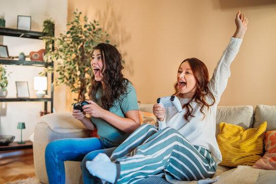 Excited young women friends playing video games at home