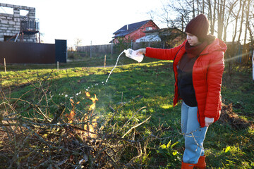 A girl burns a pile of firewood in the yard