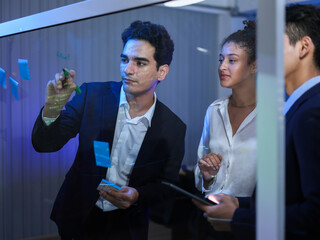 Professional team collaborating on a transparent screen in a futuristic. Writing with sticky notes and technology for strategic planning, innovative development, and successful project analysis