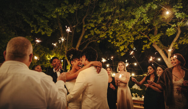 Bride and groom celebrating in a romantic outdoor wedding evening with sparklers